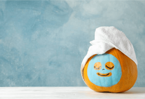 An orange which wears a mask after bathing in front of a light blue background