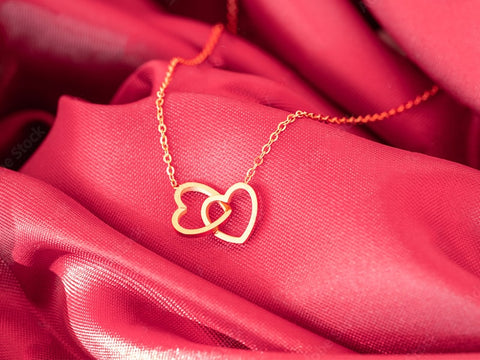 Gold heart necklace on red satin