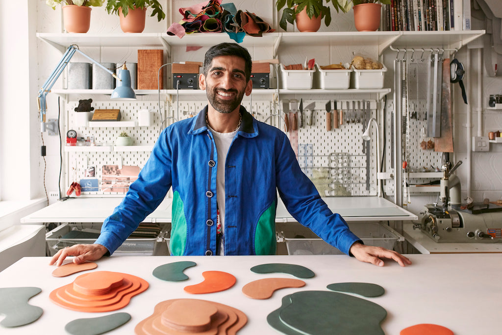 Yusuf standing at table with leather cut-outs