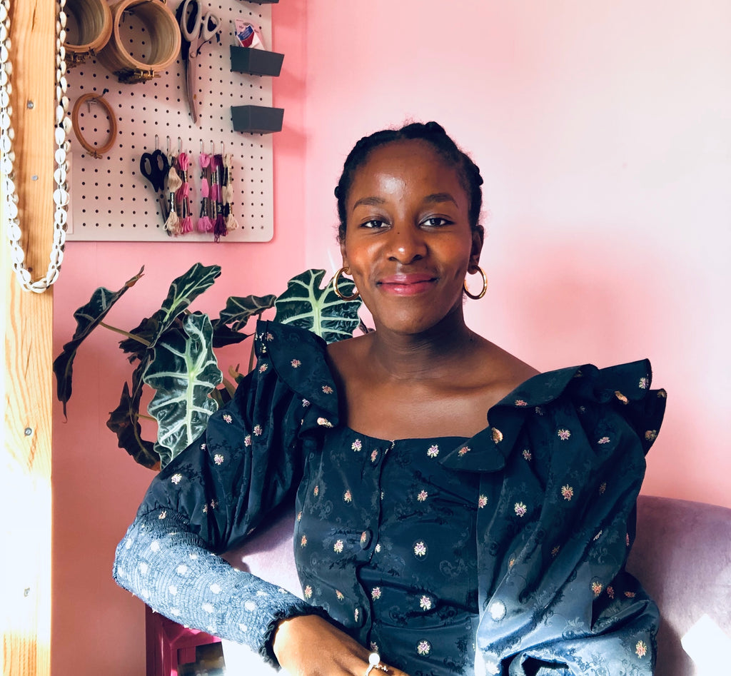 Rebeckah Kemi Apara sitting in her studio with pink wall