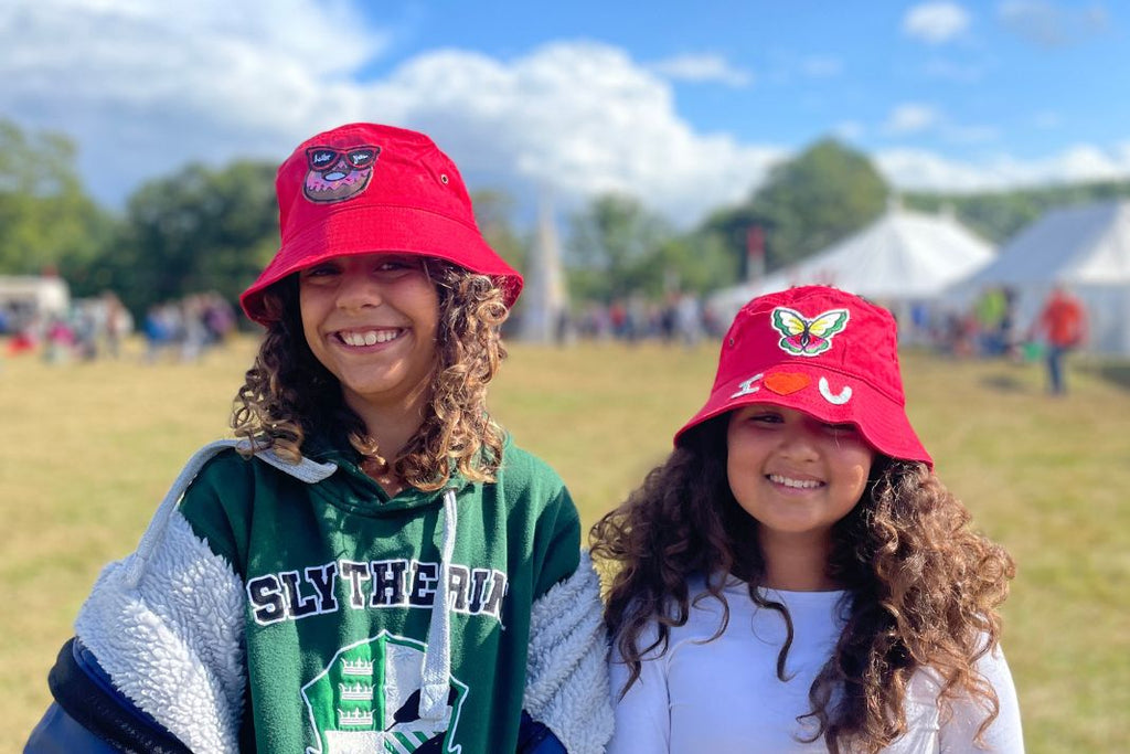 Two girls wearing matching red bucket hats with patches sewn on.