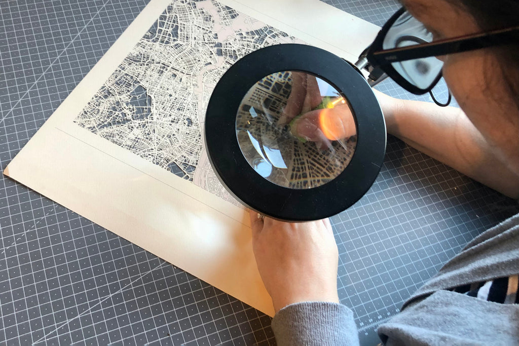 paper cutting at desk with a magnifying glass