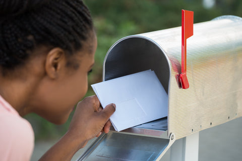 Woman Opening Her Mail Box To Retrieve Her Black Greeting Card