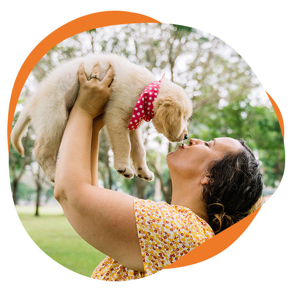 Woman affectionately holds her dog in the air