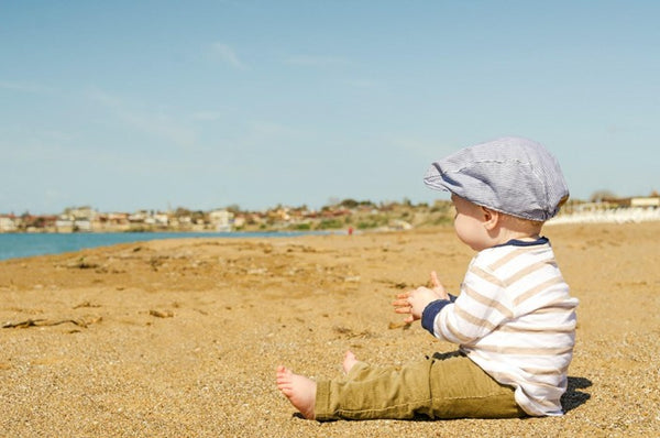 A baby dressed up and relaxing at the seaside