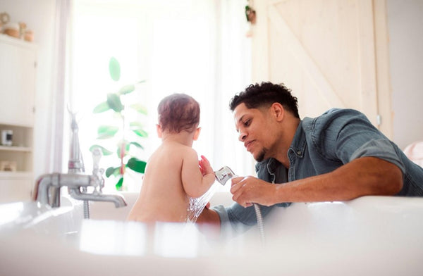 A baby having a bath with his dad