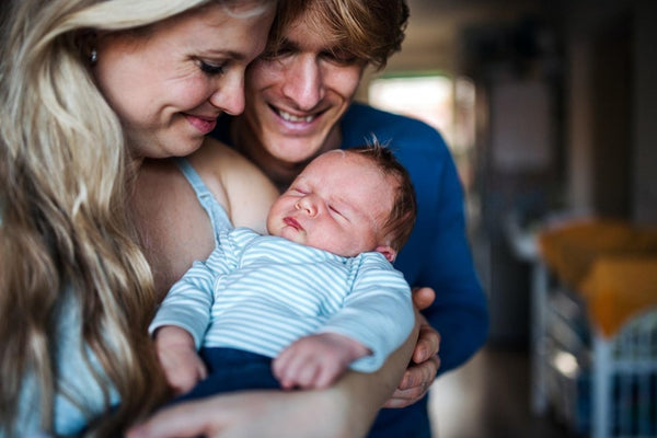 A man and wife couple coo over their beautiful newborn baby