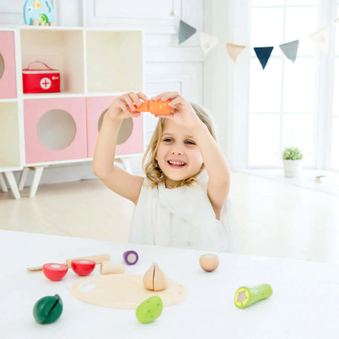 toddler girl playing with wooden vegetables