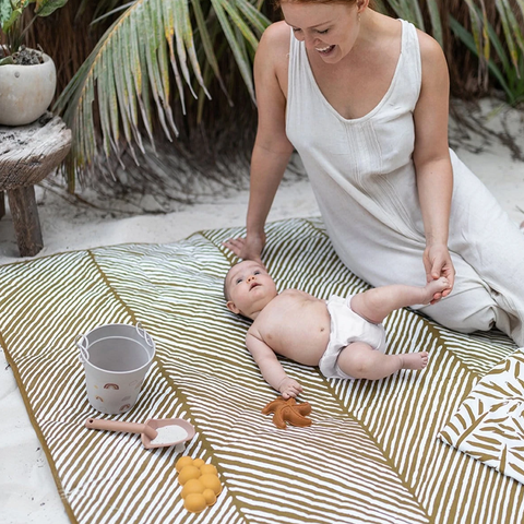 Mum and baby laying on blanket on the beach