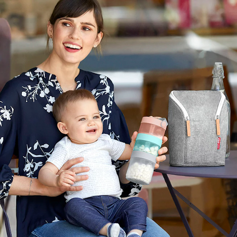 mum holding baby and baby formula food containers