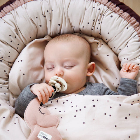 Baby sleeping on mattress with pacifier in mouth