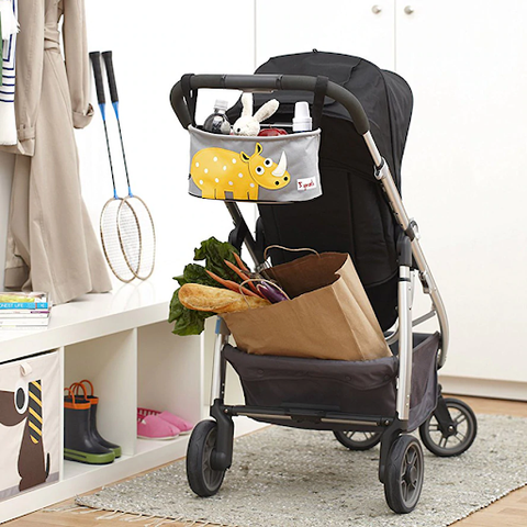 Back of stroller in room with stroller organiser hanging on stroller handles and groceries in basket of stroller