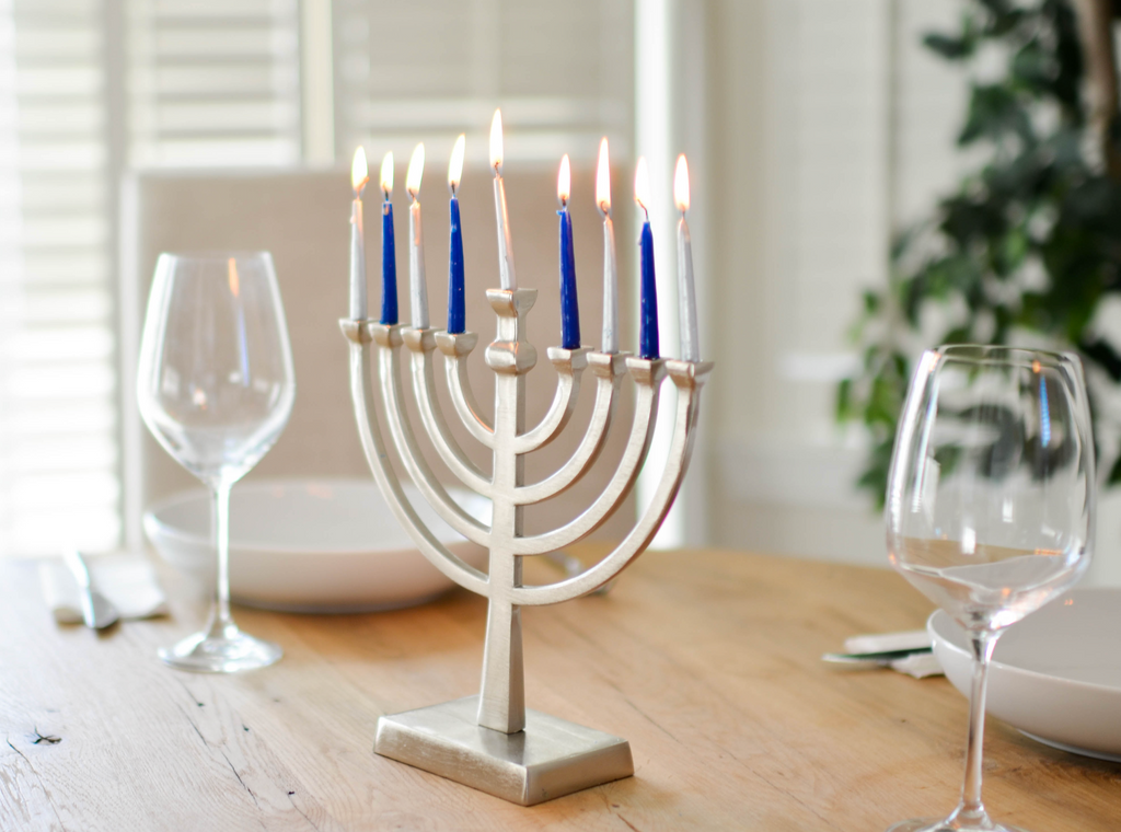 A wooden table with a Hanukkah Menorah and two empty glasses for a keto-friendly Hanukkah feast