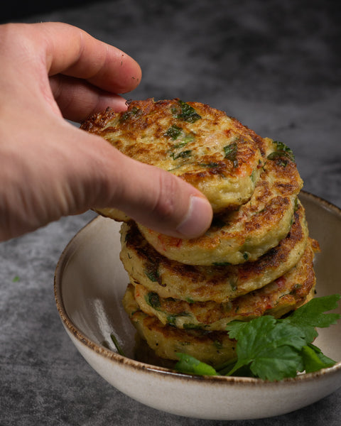 keto-friendly Hanukkah latkes served on a plate with a hand reaching for one