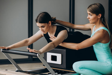 women training pilates on  reformer machine