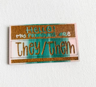 Pronoun pin that reads "Hello! My pronouns are they/them"