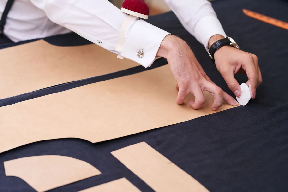 Tailor marks the measurements on linen fabric by using a sewing pattern