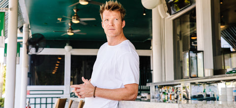 Man in white T-shirt leaning against a bar