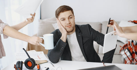 Man Sitting at Desk Bombarded with Tasks