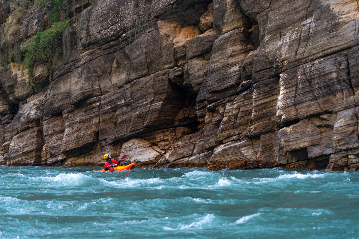 Kayaker looking at cliff wall while paddling in a river