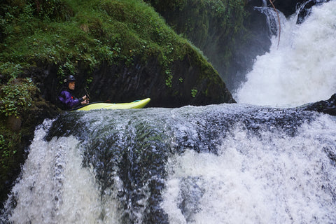 A kayaker sits above the lip of a waterfall.