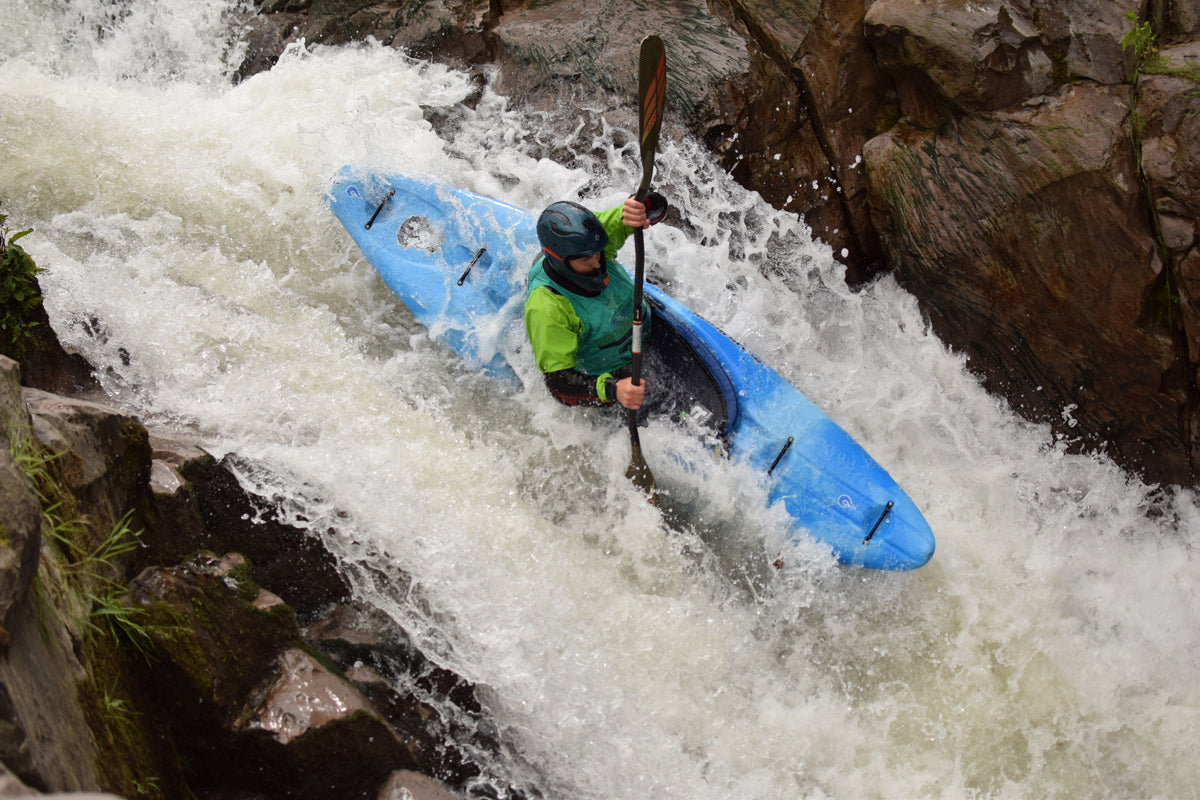 Whitewater kayaker paddling over a ledge drop on the river.