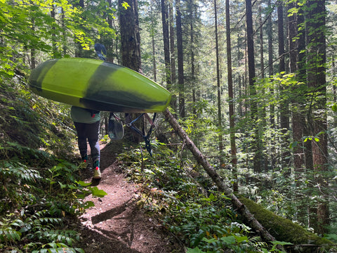 A kayaker hiking in to paddle a river in Oregon.