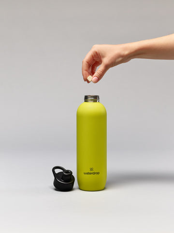 waterdrop Microlyte is being dropped into a yellow waterdrop sports bottle