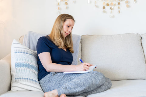 Woman writing in journal on  couch