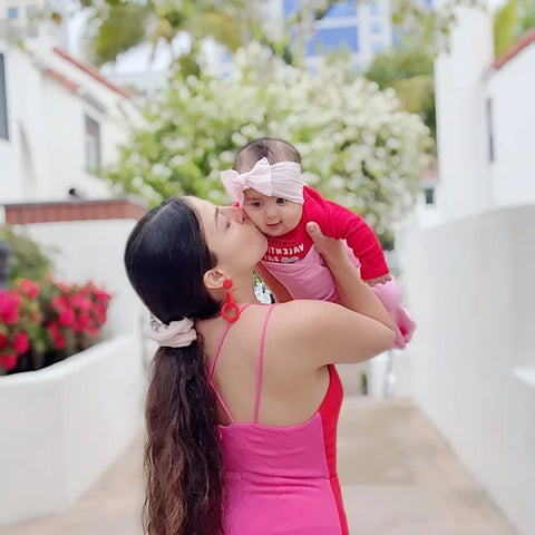 dark haired woman kissing a baby girl