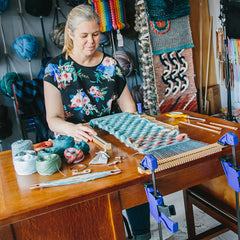 Cassandra Smith weaving a scarf on a frame loom attached to a table