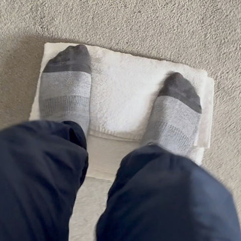 Handwoven fabric wrapped inside a towel and being stomped on to absorb excess water