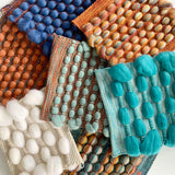 A stack of handwoven samples in bright colours and textures