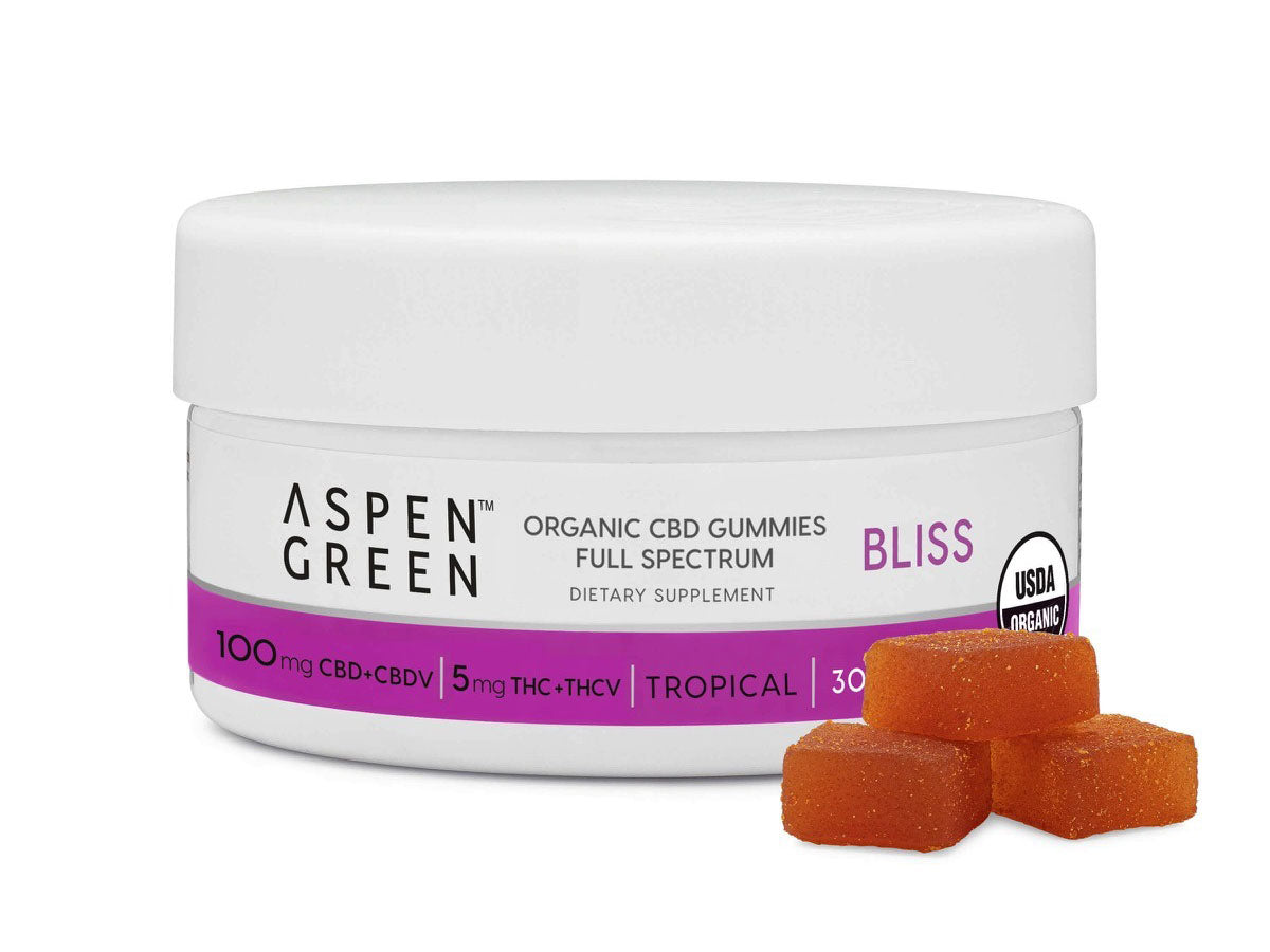 A container of Aspen Green CBD gummies with three of the gummies stacked in front of it.