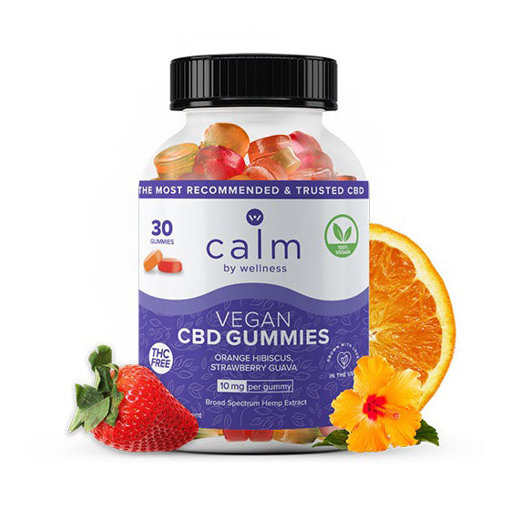 A container of Calm by Wellness CBD gummies flanked by an orange slice, a strawberry, and a hibiscus blossom.