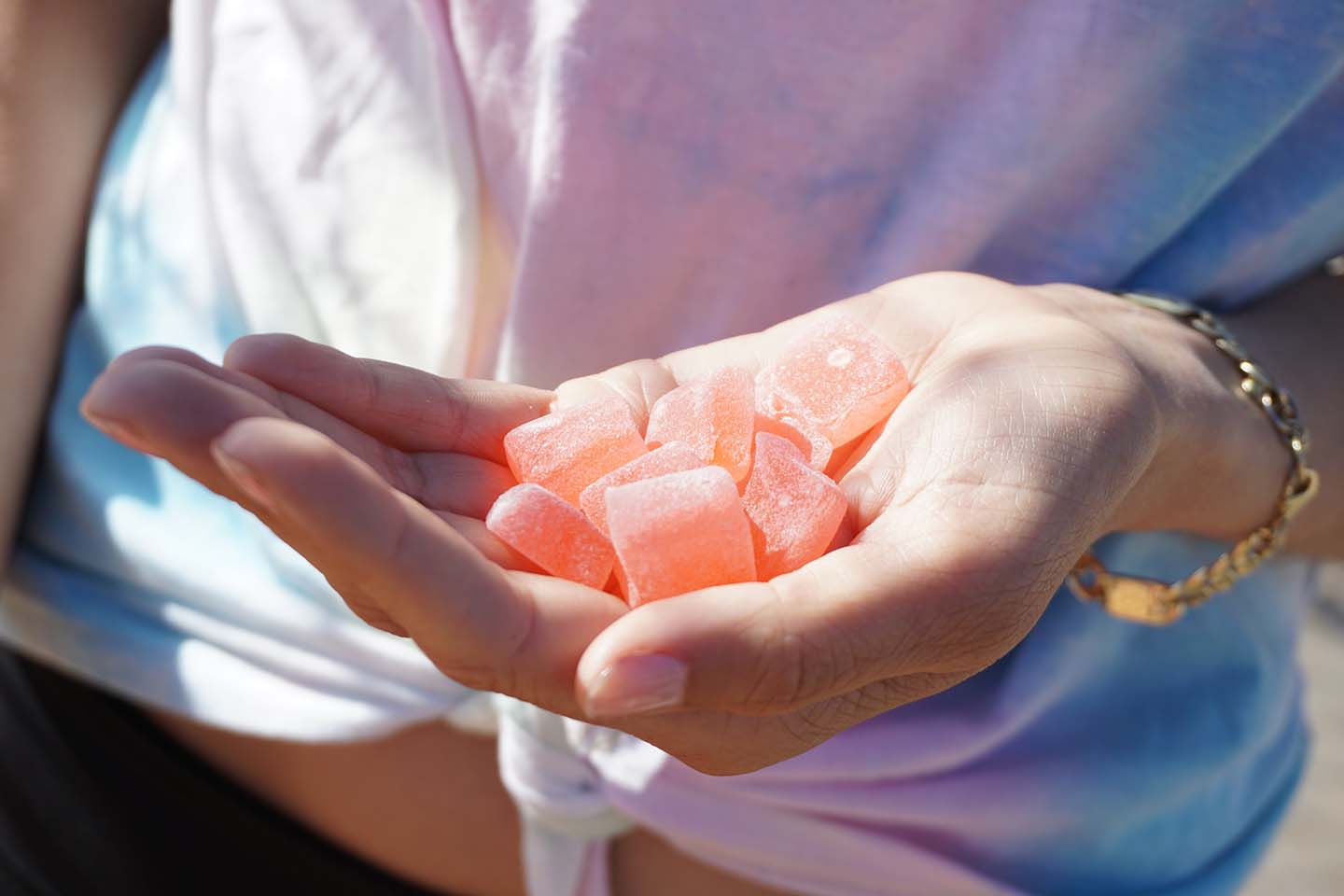 a woman's hand holding pink CBD gummies