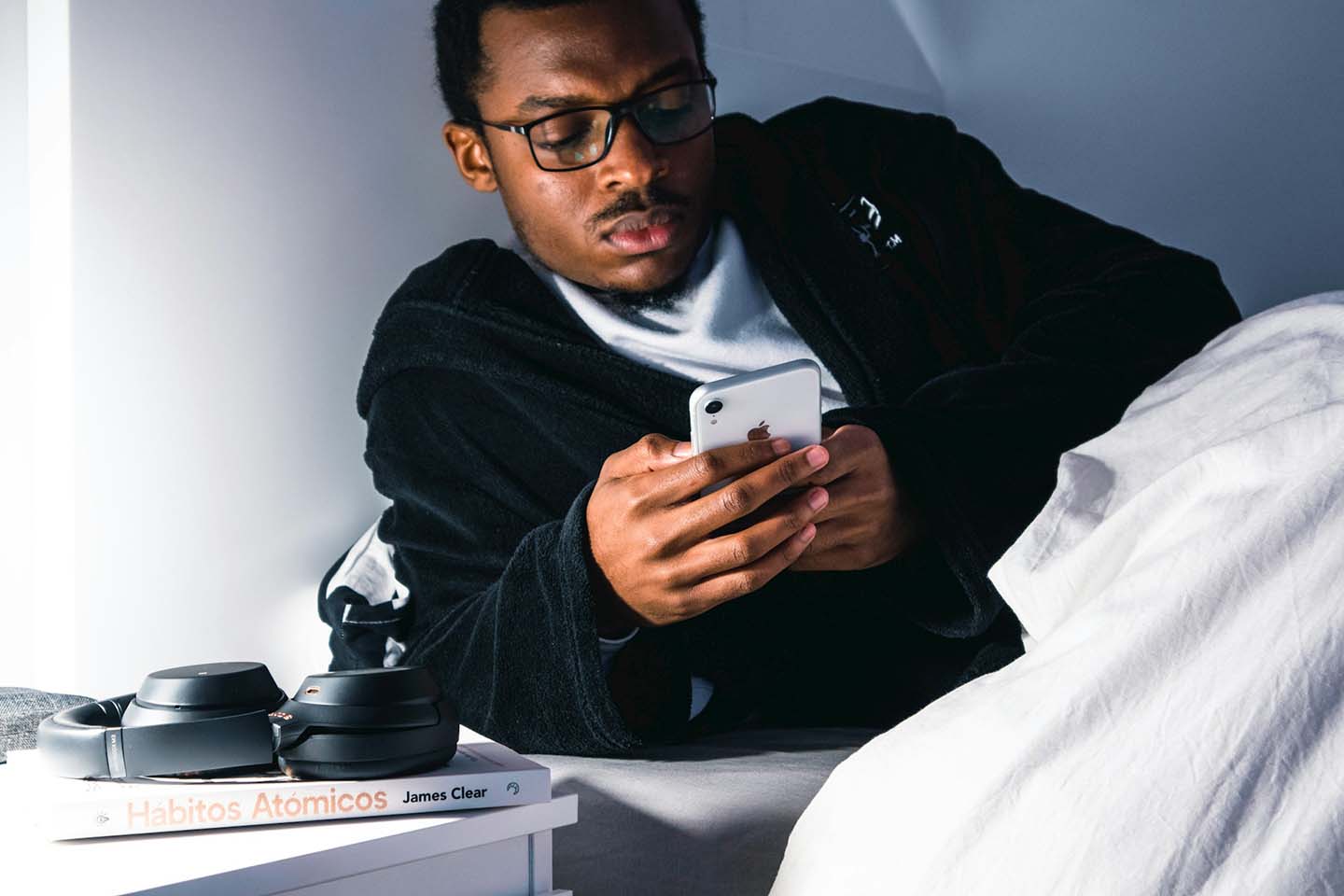 a man looking a his smartphone while on bed