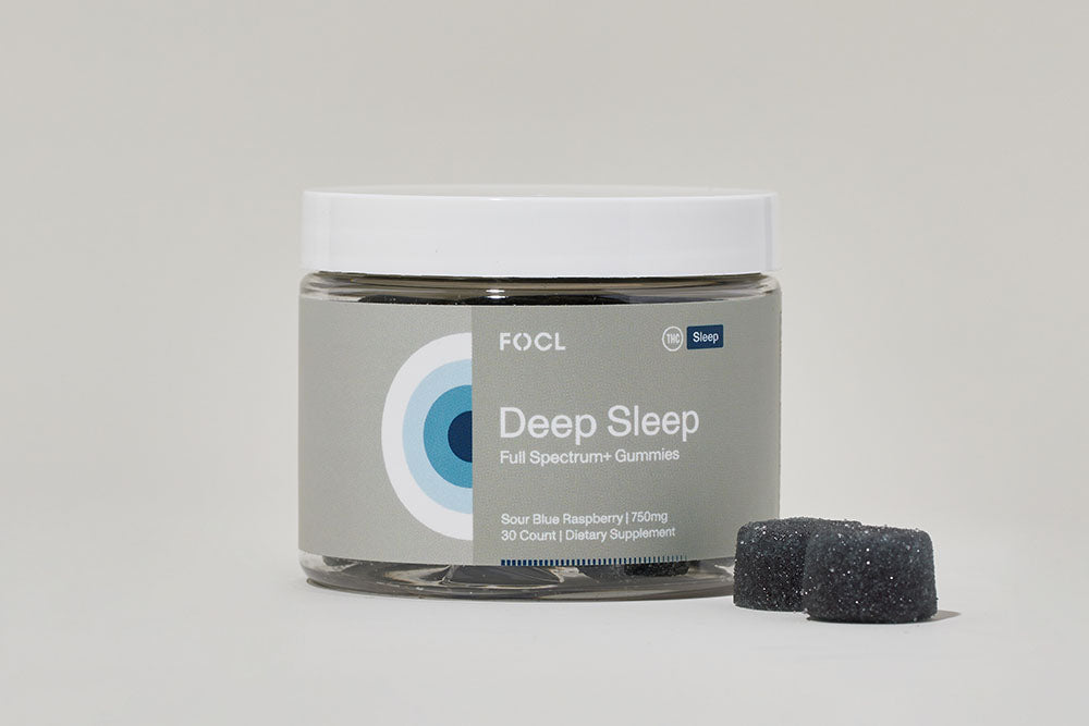Jar of FOCL Deep Sleep Gummies with two dark blue gummies