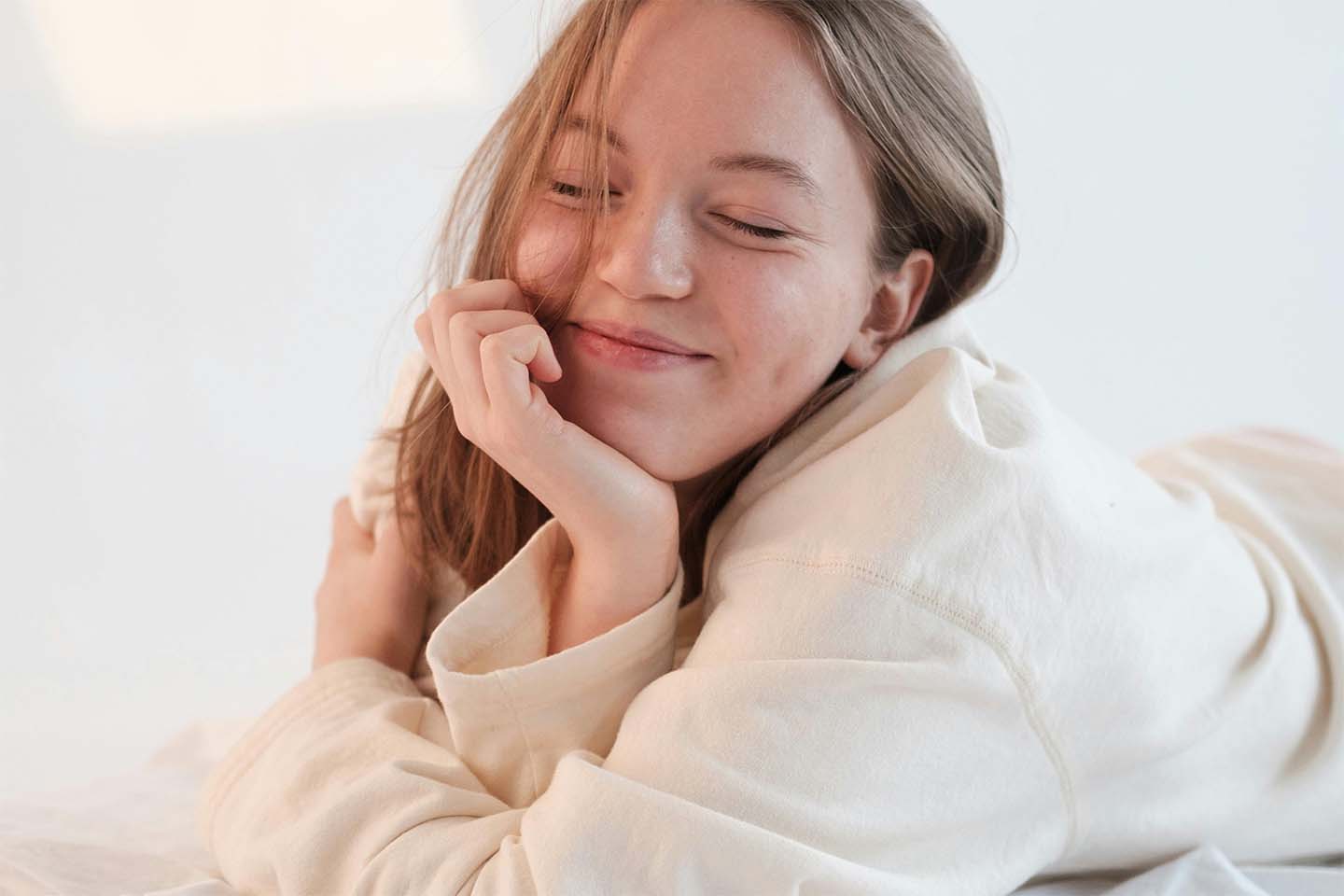 a woman smiling and chilling on bed in the morning