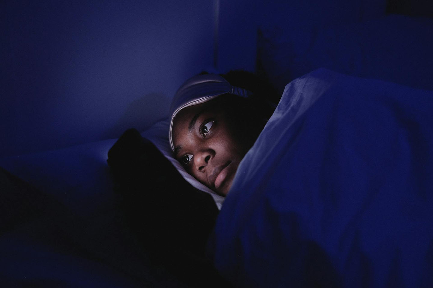 woman looking at a phone in bed at night