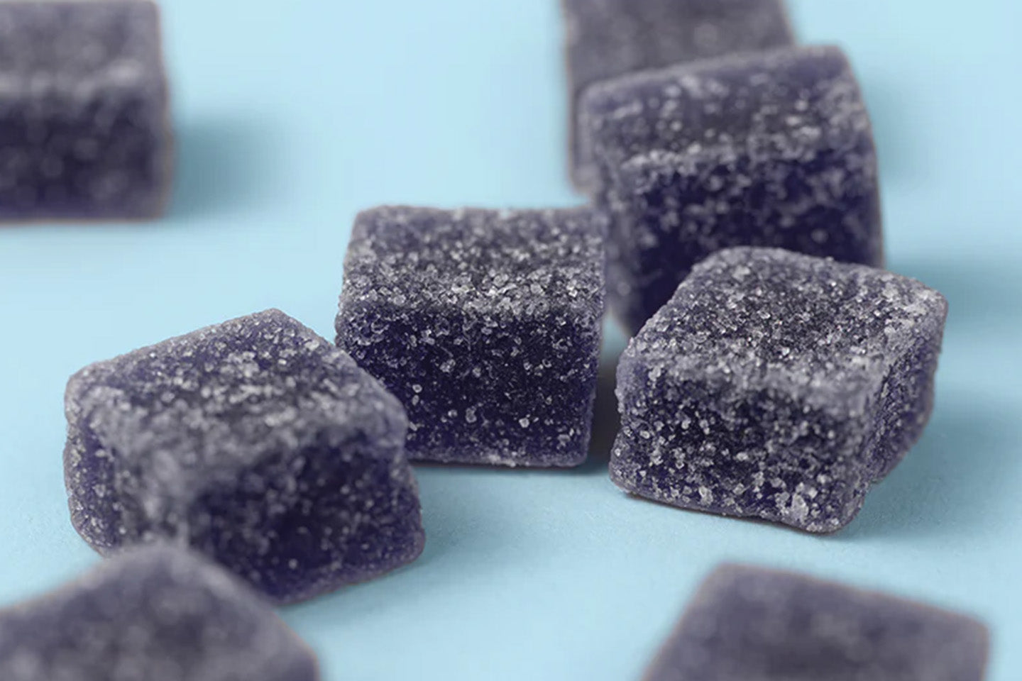 Dark blue gummies on light blue surface