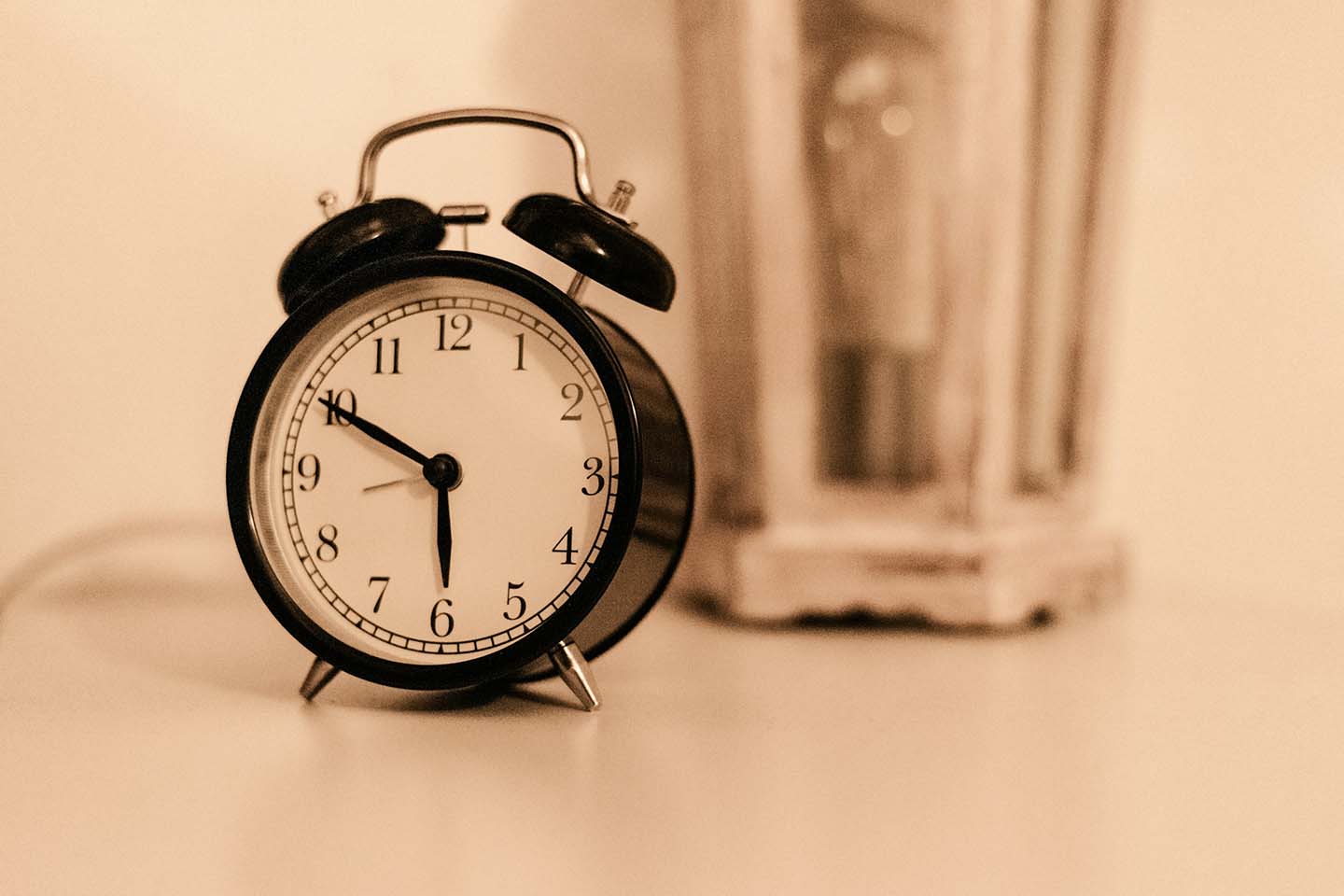 close-up photo of a black and white alarm clock on a bedside table