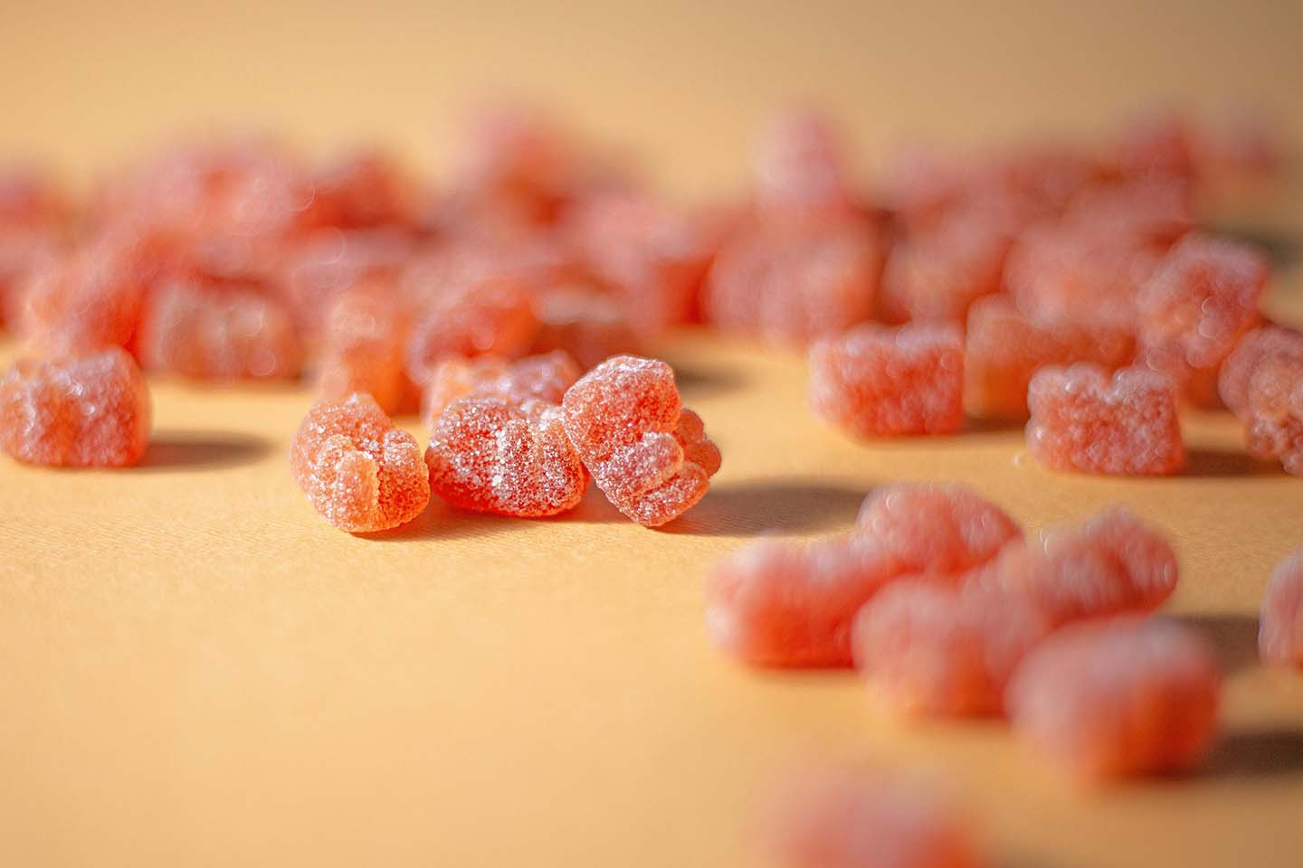 close-up photo of several ored-range gummy bears on a brown surface