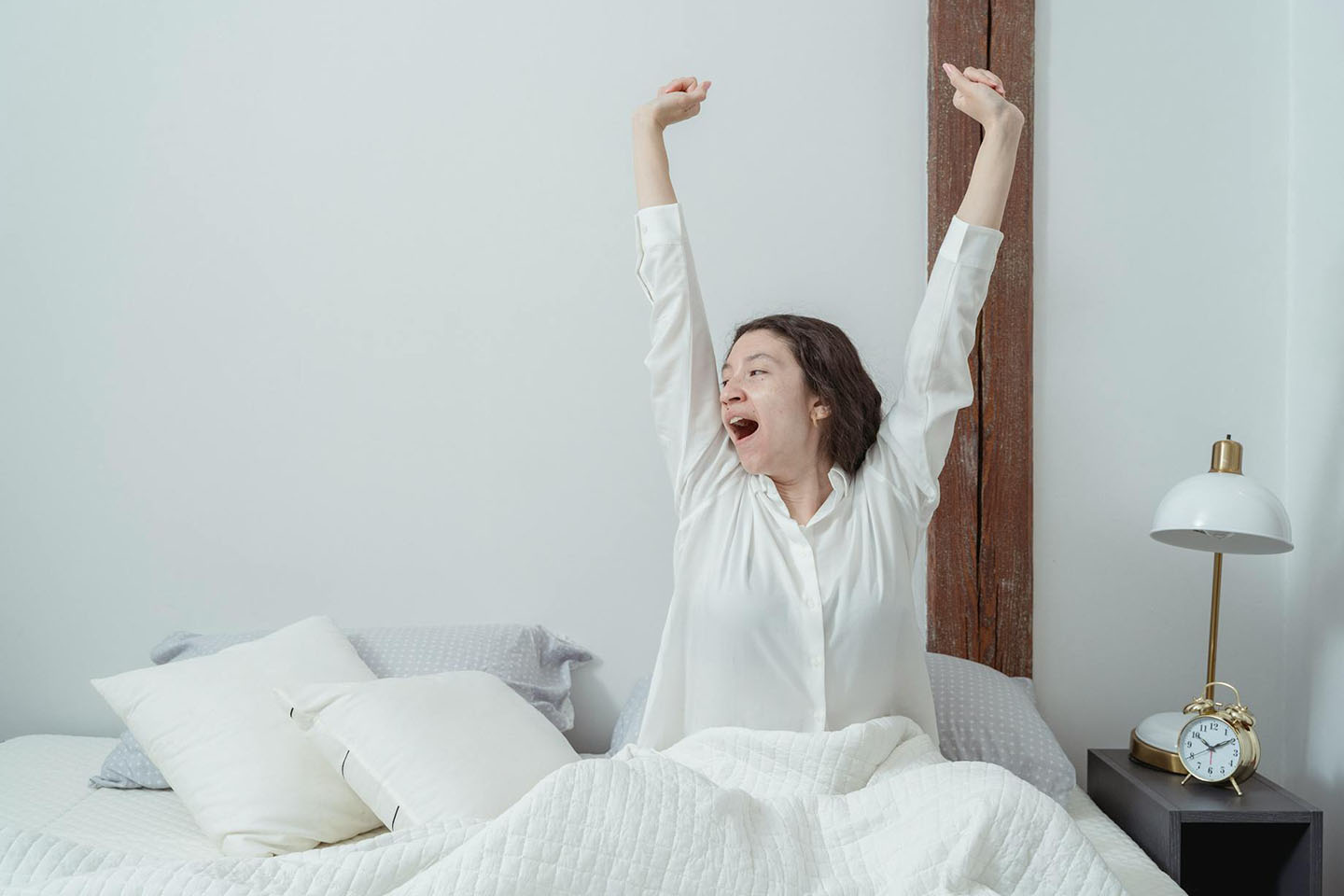 A woman sitting and stretching in bed after waking up