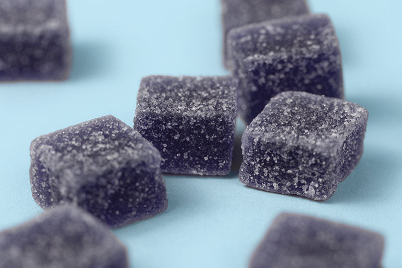 dark blue gummies dusted with sugar on blue surface