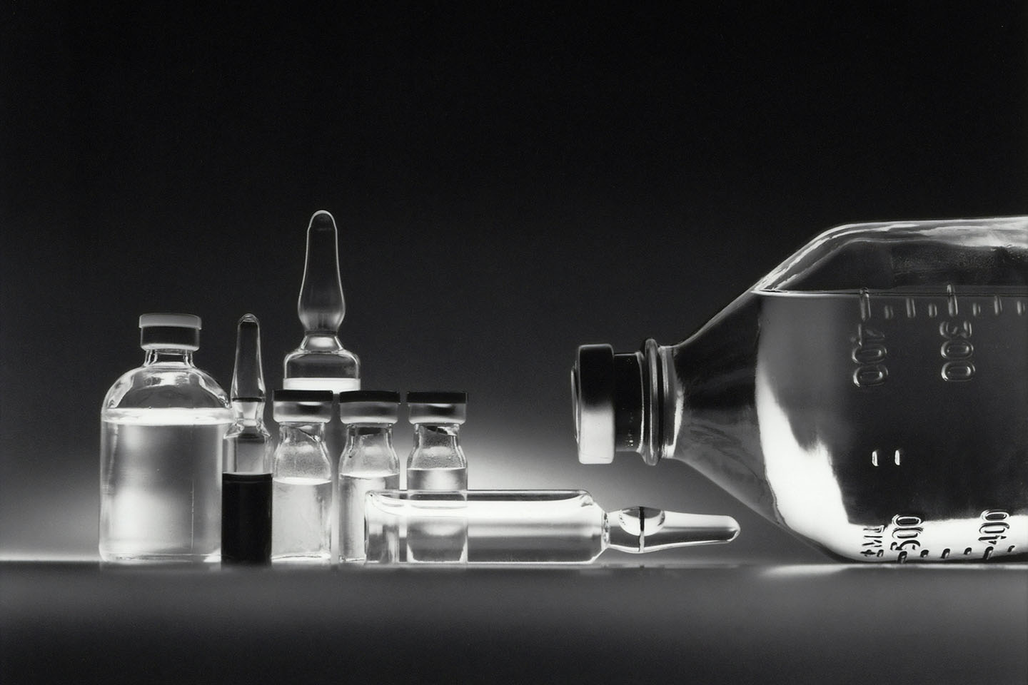 a black and white monochrome photo of jars and vials of liquid