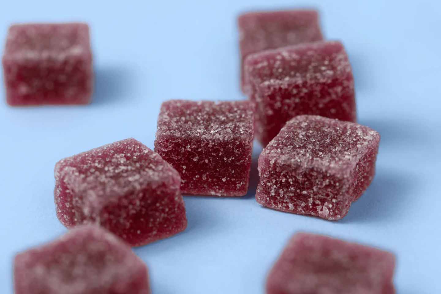 Reddish-purple CBD gummies on blue surface