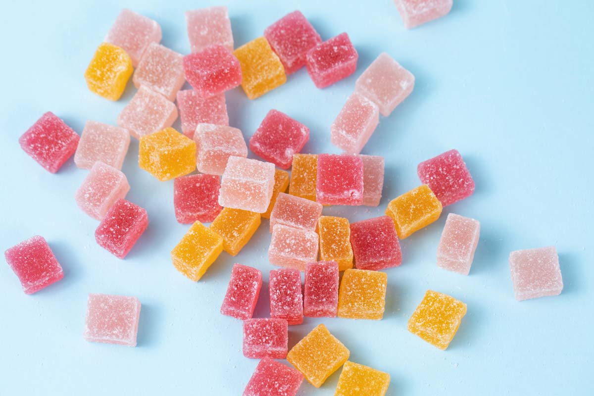 Mix of red, yellow, and pink CBD gummies on a blue background