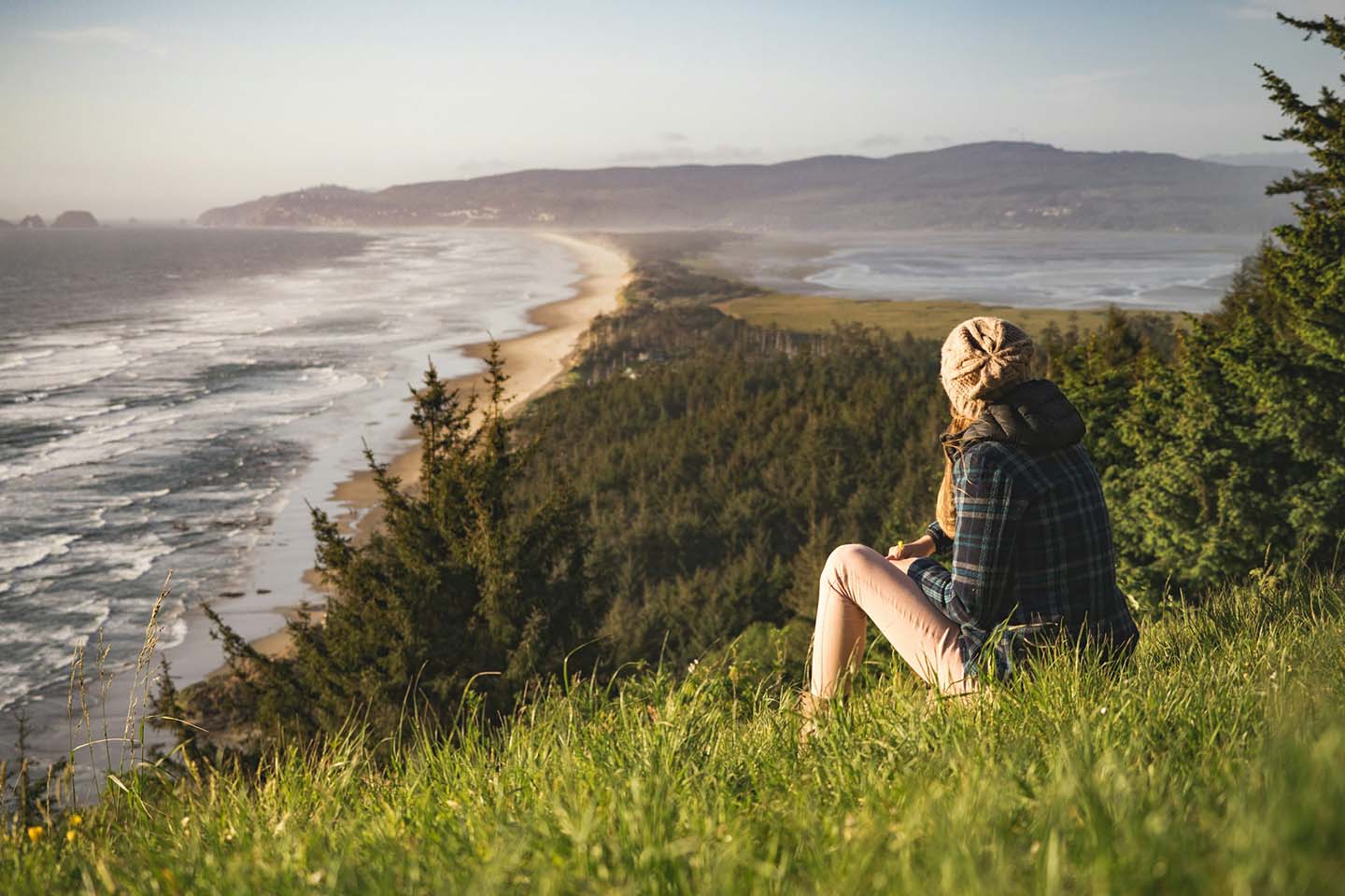 a person sitting on top of a hill and looking at the ocean