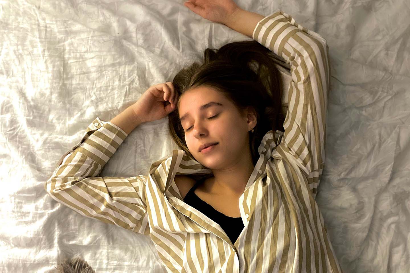Woman in white and black striped long sleeve shirt lying on bed